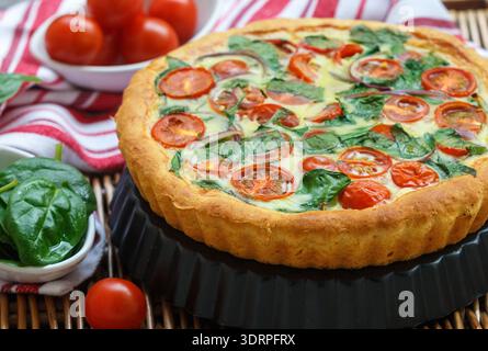 Summer outdoor tart, pie of fresh vegetables - tomatoes, spinach and red onion with cream and cheese. Selective focus Stock Photo