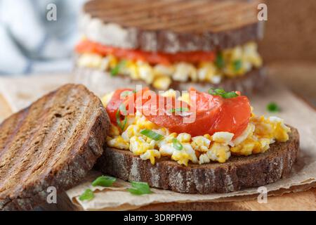 Scrambled eggs and smoked salmon on rye bread with green onions. A sandwich for breakfast. Selective focus Stock Photo