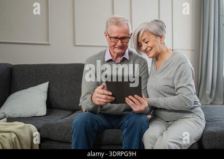 Senior old couple with tablet watching video online. Husband wife spending time together at home. Happy modern mature senior cou Stock Photo