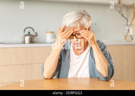 Headache pain, Unhappy middle aged senior woman suffering from headache sick rubbing temples at home. Mature old senior grandmot Stock Photo