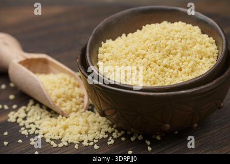 Raw organic couscous in a bowl on the table. Selective focus Stock Photo