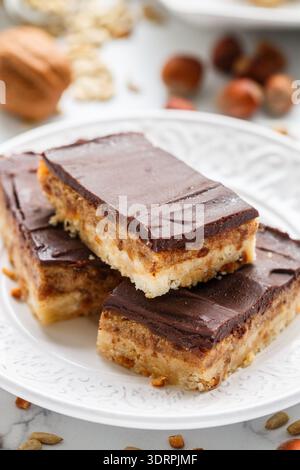 Homemade Vegan cocoa dates chocolate bars with coconut, hazelnuts, walnuts and sunflower seeds on a white background. Healthy de Stock Photo
