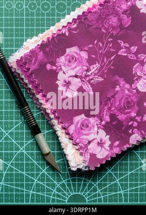 Fabric patchwork quilting patterned quilting squares on a green cutting mat with a craft knife background backdrop. Stock Photo