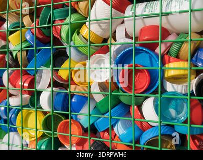 Large pile of plastic bottle caps in a mesh recycling container for secondary raw materials collection and environmental protection concept Stock Photo