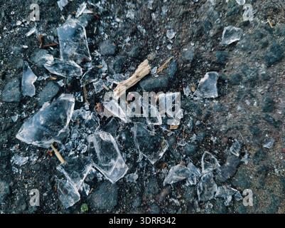 Shattered glass fragments scattered on dark pavement at Ors vezer tere, Budapest. A raw and gritty abstract capture of urban textures and the unpolish Stock Photo