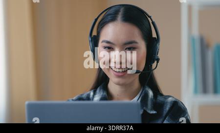 Asian Korean business woman student headset headphones talking online video call at home looking laptop girl female conference chat distant job Stock Photo