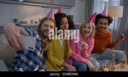 Happy birthday party at home friends taking selfie mobile phone multiethnic diverse celebrating African women Caucasian men photo recording video vlog Stock Photo