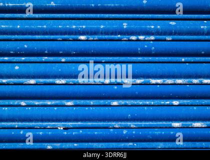 Full-frame texture of a weathered blue corrugated metal shutter, featuring bold horizontal ridges and subtle surface wear, suitable for backgrounds Stock Photo