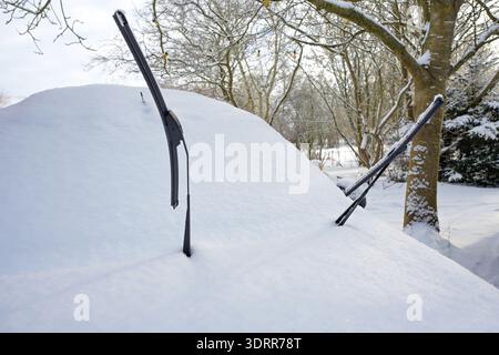 Snow-covered car with raised wipers to prevent them from freezing to the windshield, traffic and transportation problems in the cold winter season, co Stock Photo