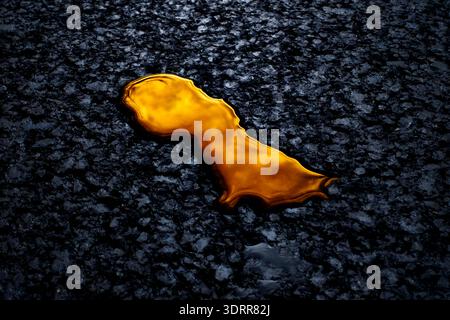 a drop of iridescent golden oil on the asphalt Stock Photo