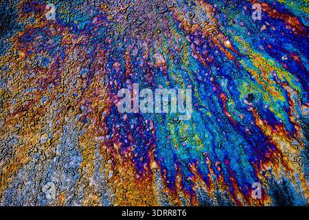 a photograph of an oil or petrol stain on a wet asphalt or pavement surface, a phenomenon called iridescence. interference of light waves reflecting o Stock Photo