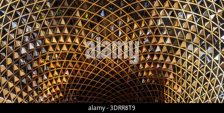 a modern architectural structure with a complex, curved design made of gold-tone metal and mirrored triangles Stock Photo