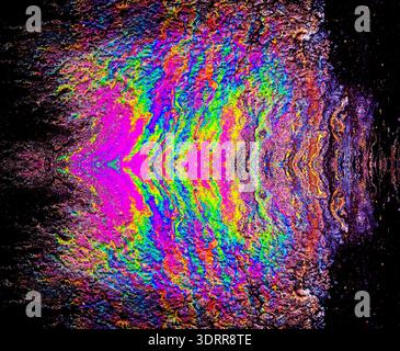a photograph of an oil or petrol stain on a wet asphalt or pavement surface, a phenomenon called iridescence. interference of light waves reflecting o Stock Photo