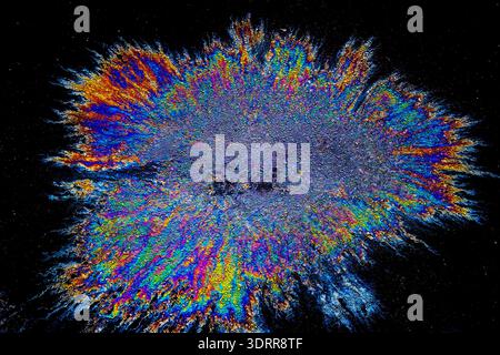 a photograph of an oil or petrol stain on a wet asphalt or pavement surface, a phenomenon called iridescence. interference of light waves reflecting o Stock Photo