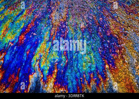 a photograph of an oil or petrol stain on a wet asphalt or pavement surface, a phenomenon called iridescence. interference of light waves reflecting o Stock Photo