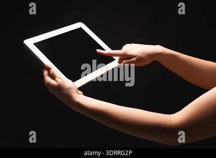 Hand Interacts With a Blank Tablet Screen in a Dark Setting With Focus on Technology Use Stock Photo