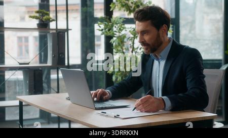 Successful Caucasian businessman manager typing laptop writing notes in office professional male accountant entrepreneur leader write data accounting Stock Photo