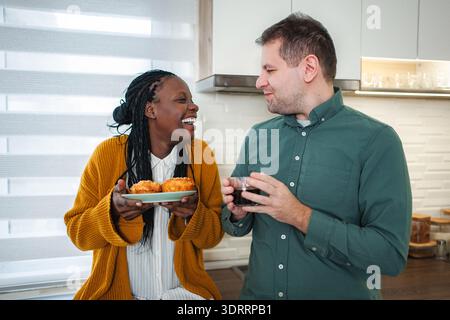 Smiling diverse couple enjoying morning coffee and breakfast Stock Photo