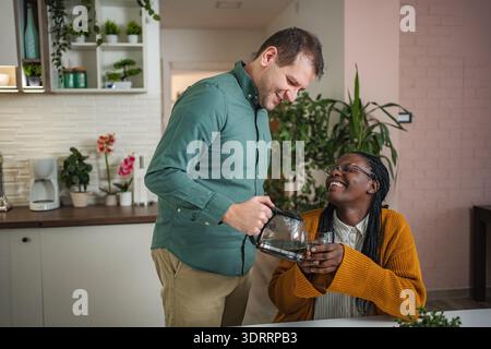 Man pouring coffee for laughing woman in kitchen Stock Photo