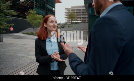 Caucasian businessman businesswoman coworkers partners discuss project in city business people colleagues collaborative talking details task Stock Photo