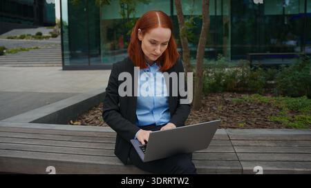 Pensive Caucasian businesswoman think solution working online laptop city bench concentrated business woman thinking answer report writing journalist Stock Photo