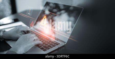 A close up of hands using a laptop with multiple red warning signs and alert pop-ups on the screen. Concept of cyber security breach, computer virus, Stock Photo