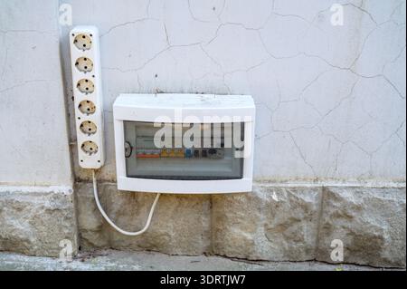 Electrical panel and power sockets mounted on a cracked exterior wall of a building. Concept of home electrical maintenance, power supply infrastructu Stock Photo