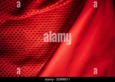 Red technical sports fabric texture with breathable mesh and smooth polyester panel macro background for athletic apparel manufacturing and design Stock Photo