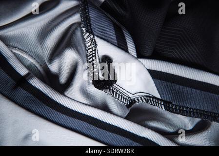 Technical sports garment detail with overlock stitched seam and striped ribbed cuff macro textile background for athletic apparel manufacturing design Stock Photo