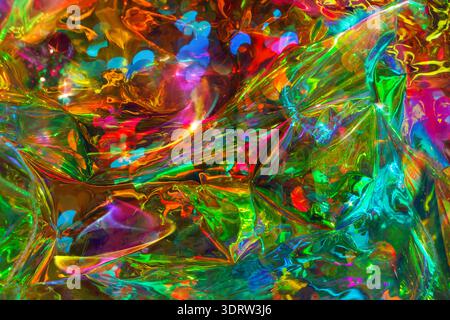 Abstract colorful background featuring bright reflections of green, red, blue, and yellow on crumpled plastic, creating a dynamic visual effect Stock Photo