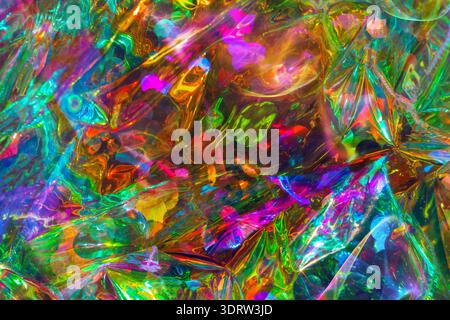 Abstract colorful background featuring bright reflections of green, red, blue, and yellow on crumpled plastic, creating a dynamic visual effect Stock Photo