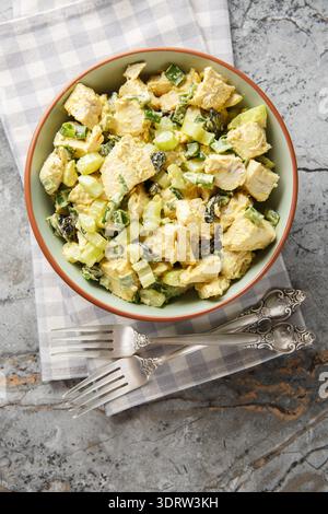 Curry chicken salad with vegetables and yogurt dressing close-up in a bowl on the table. Vertical top view from above Stock Photo
