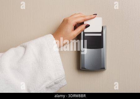 Hand Placing Card in Wall Panel for Access to Room in Hotel Setting During Daytime Stock Photo