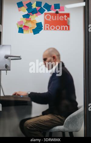 Business professional works at a desk in a quiet room with colorful sticky notes on the door Stock Photo