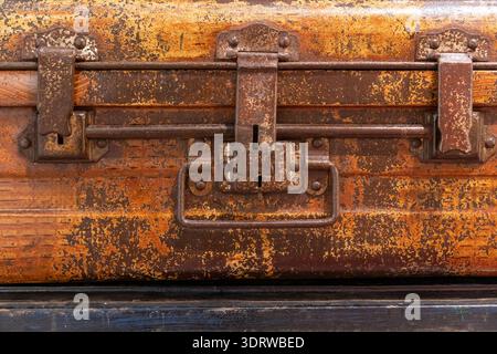 Close-up of a rusty vintage suitcase lock and weathered leather trunk showing patina, flaking finish and rich surface texture Stock Photo