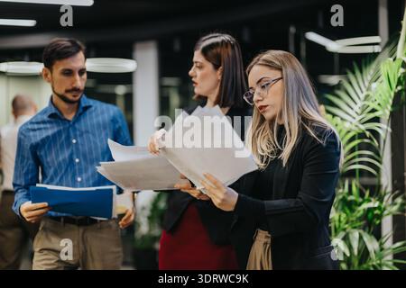 Business team reviews documents in a modern office during a collaborative work session Stock Photo