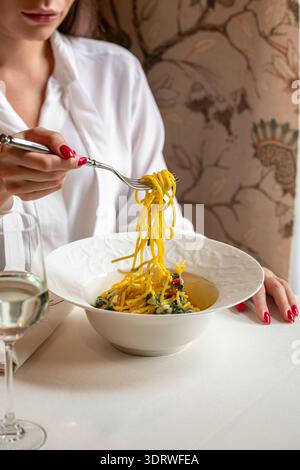 Woman eating pasta in elegant restaurant setting Stock Photo