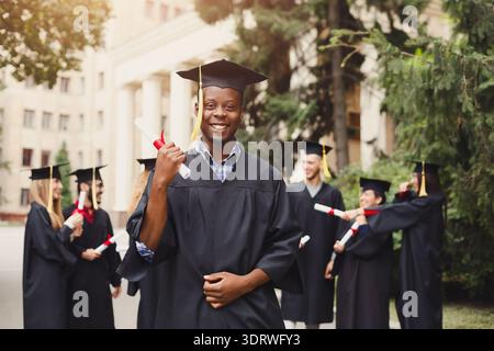 Graduation Celebration With Graduates Holding Diplomas in Outdoor Setting During Sunny Day Stock Photo