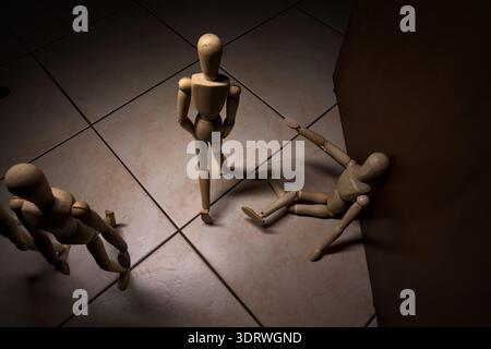 Wooden mannequin pretengind to sit on a street and to lean on a wall  raising its hand toward passing people in the act of begging  with other wooden Stock Photo