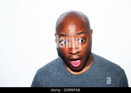Close-up portrait of a thoughtful middle-aged man in a gray t-shirt, touching his face with a contemplative expression, soft studio lighting for profe Stock Photo