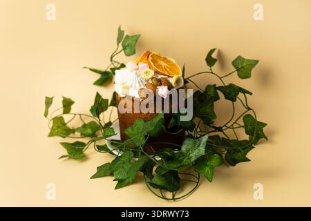 Traditional glazed Easter cake with decorative green leaves, minimalist composition on peach colored background Stock Photo