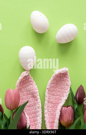Easter Eggs with Bunny Ears and Tulips on Green Background. Spring Holiday Composition Stock Photo