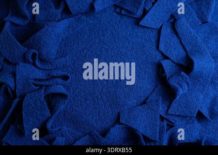 Bright blue wool fabric scraps placed around an empty center create a circular textured frame with copy space suitable for textile, craft, and sustain Stock Photo