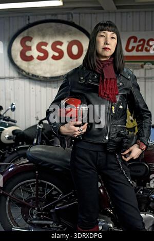 Japanese female Rockers subculture members posing in front a vintage Esso sign in motorcycle garage Stock Photo
