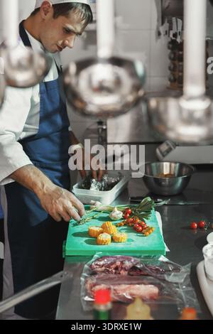 Chef Prepares Ingredients in a Busy Kitchen During the Dinner Service for a Special Menu Stock Photo