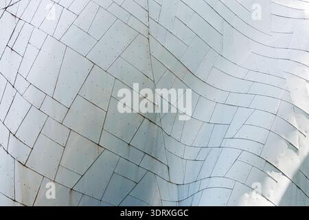 Abstract close-up of curved metal facade with tiled panels, seams, and rivets; modern architecture texture in cool tones, minimal background for desig Stock Photo
