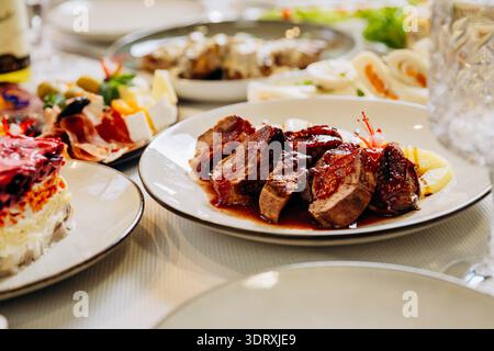 Grilled meat with sauce served on elegant festive restaurant dinner table Stock Photo