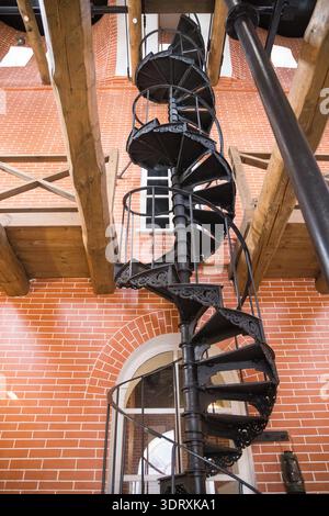 High black spiral staircase (winding staircase) in a red brick building, seen from below Stock Photo