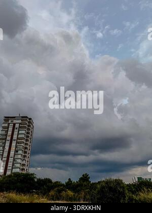 Dramatic storm clouds over residential building, dark sky before rain with urban landscape and approaching thunderstorm Stock Photo