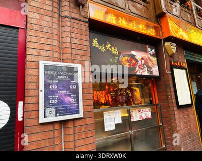 Manchester, UK - January 29, 2026: Street view of a Chinese barbecue storefront in Manchester with hanging meats and illuminated neon signs. Stock Photo